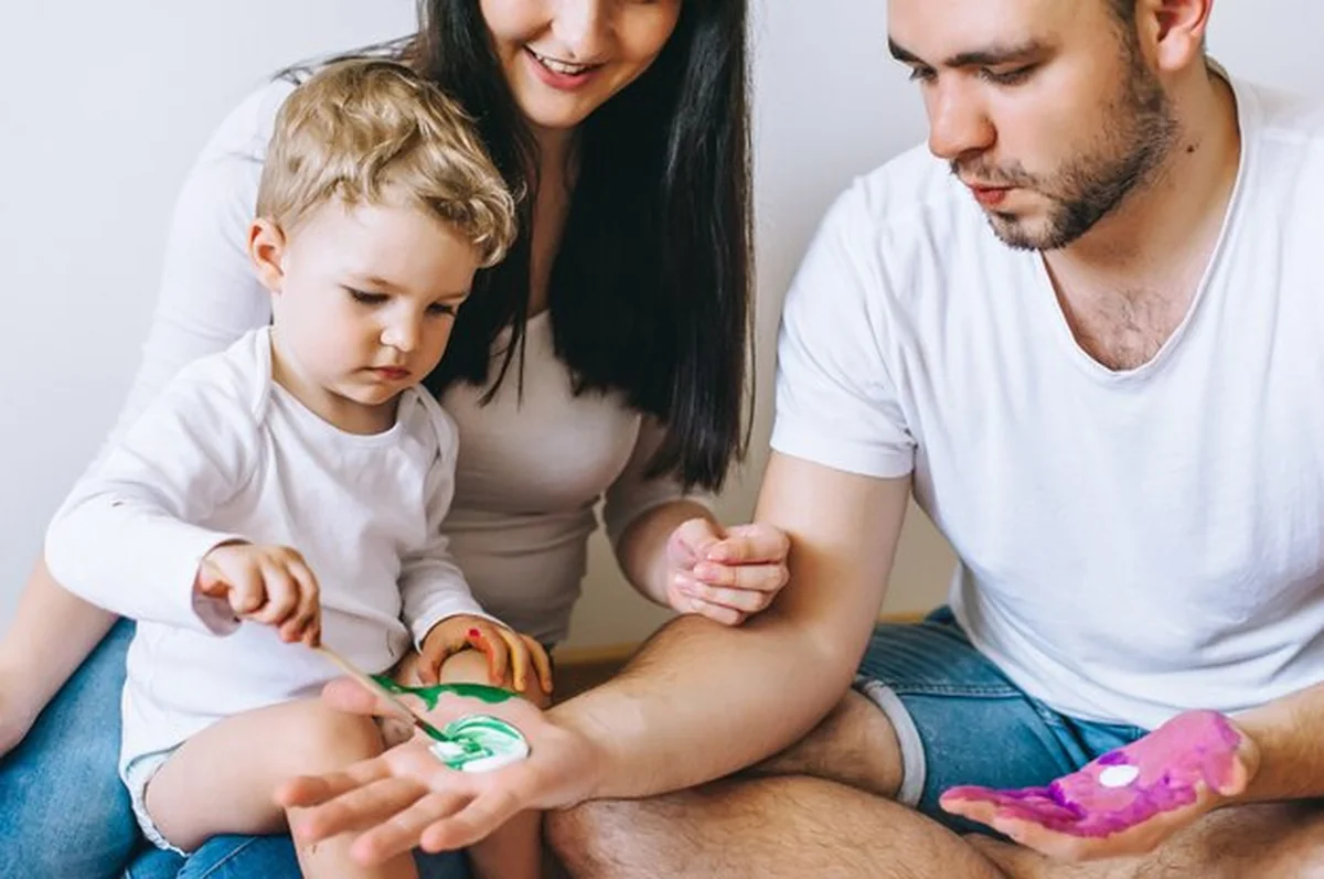 Matka, ojciec i syn malują obrazek rękami